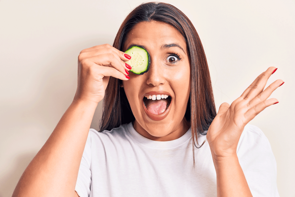 Woman with cucumber slice over eye, natural remedies for eye bags